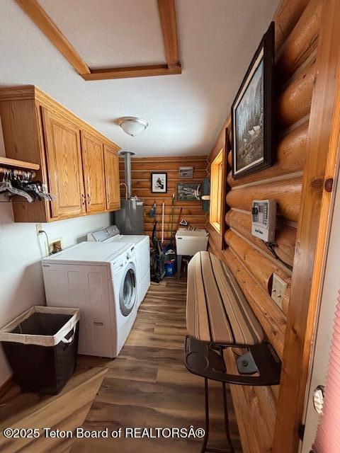 laundry room featuring washer and dryer, water heater, cabinet space, and wood finished floors