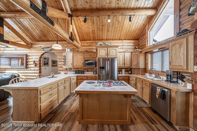 kitchen featuring a peninsula, a sink, stainless steel appliances, tile counters, and beamed ceiling