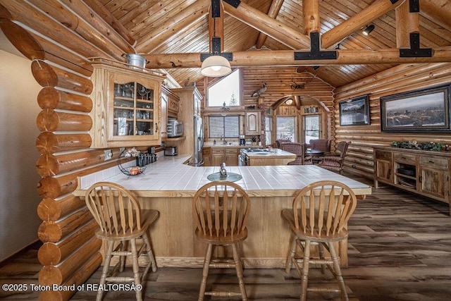 kitchen featuring high vaulted ceiling, beam ceiling, tile counters, dark wood-type flooring, and glass insert cabinets