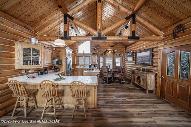 kitchen with a peninsula, beam ceiling, dark wood-style flooring, glass insert cabinets, and appliances with stainless steel finishes