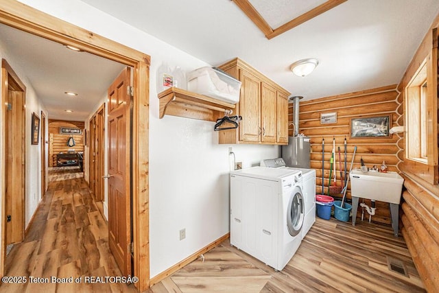 clothes washing area featuring visible vents, cabinet space, separate washer and dryer, gas water heater, and rustic walls