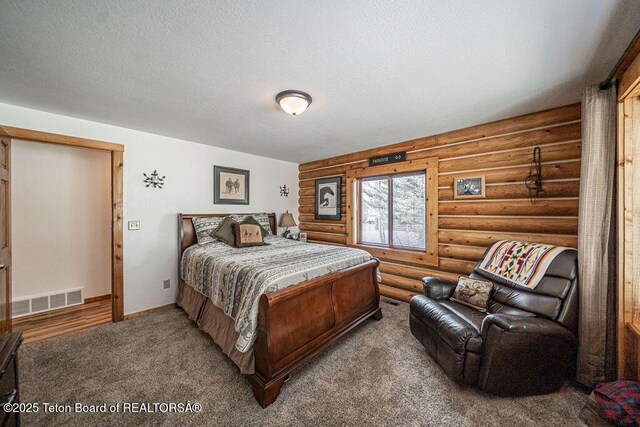 carpeted bedroom with rustic walls, visible vents, baseboards, and a textured ceiling