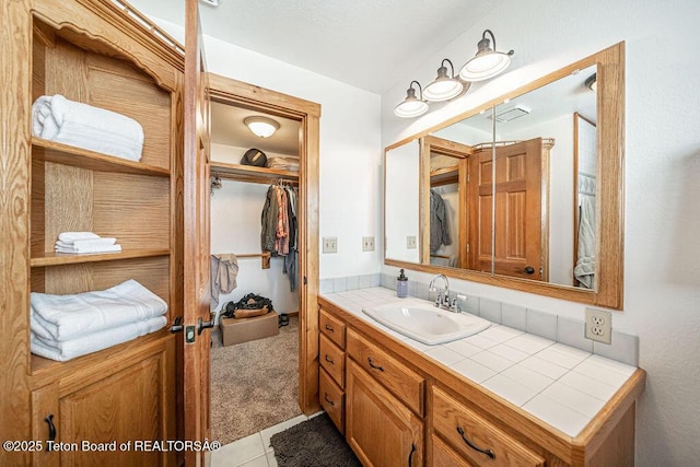 bathroom featuring tile patterned flooring, a spacious closet, and vanity