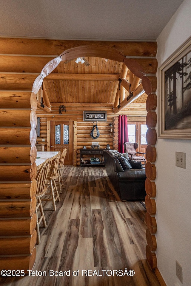 living area featuring lofted ceiling with beams, wood finished floors, and wooden ceiling