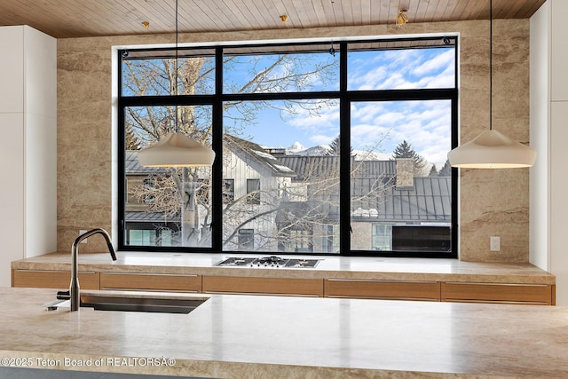 room details featuring gas cooktop, wood ceiling, light countertops, and a sink