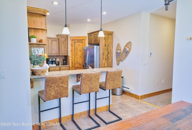 kitchen with a breakfast bar, stainless steel refrigerator with ice dispenser, open shelves, baseboard heating, and a peninsula