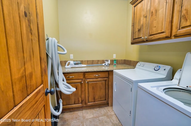 washroom with light tile patterned floors, cabinet space, and washer and dryer