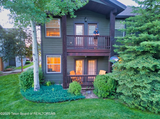 rear view of property with a yard and a balcony