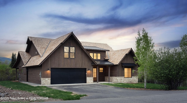 1777 Telemark Trl, Driggs, ID 83422 - view of front of house with stone siding, asphalt driveway, metal roof, a standing seam roof, and an attached garage