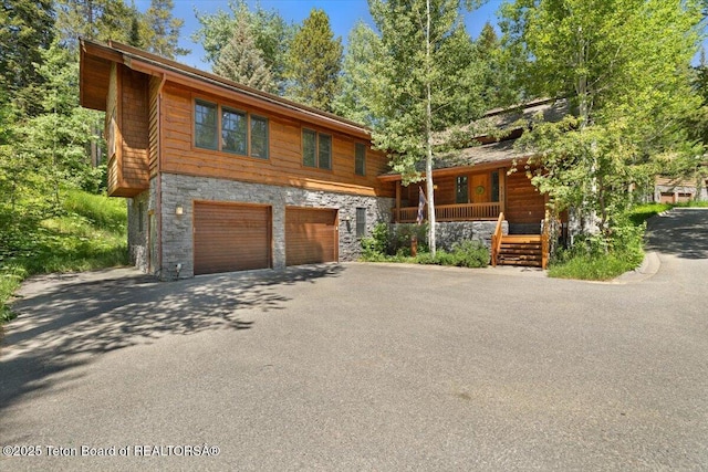 3102 W Arrowhead Rd, Teton Village, WY 83025 - view of front of home with stone siding, a porch, asphalt driveway, and an attached garage