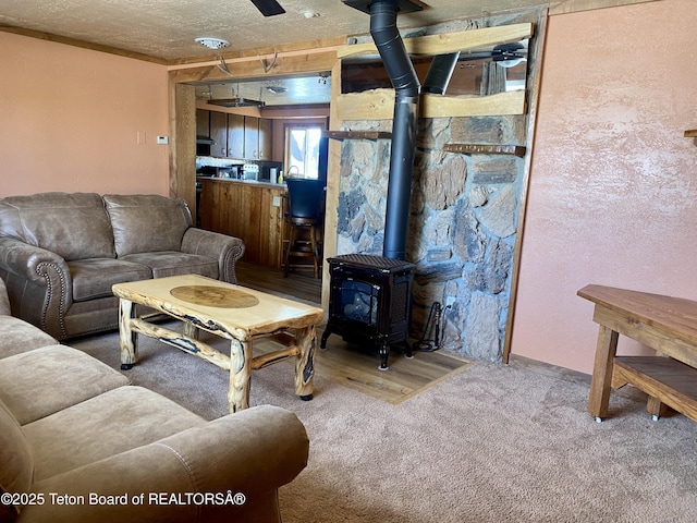 carpeted living area featuring a textured ceiling and a wood stove