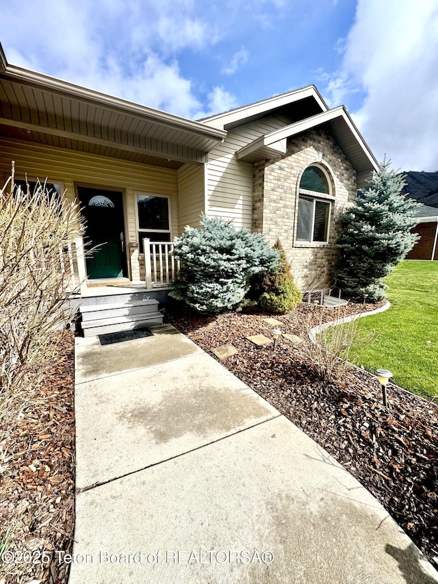 30 Miles Mdw, Afton, WY 83110 - doorway to property with covered porch, brick siding, and a lawn