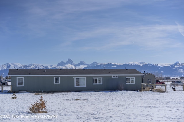 snow covered rear of property featuring fence and a mountain view