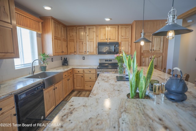 kitchen with a sink, decorative backsplash, light stone counters, and black appliances