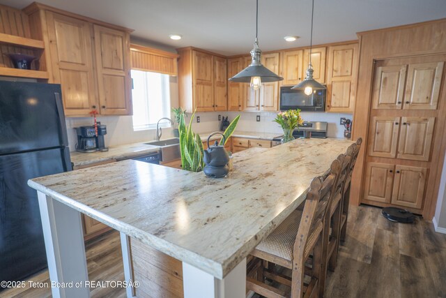 kitchen featuring a breakfast bar, stainless steel electric stove, dark wood-style flooring, freestanding refrigerator, and black microwave