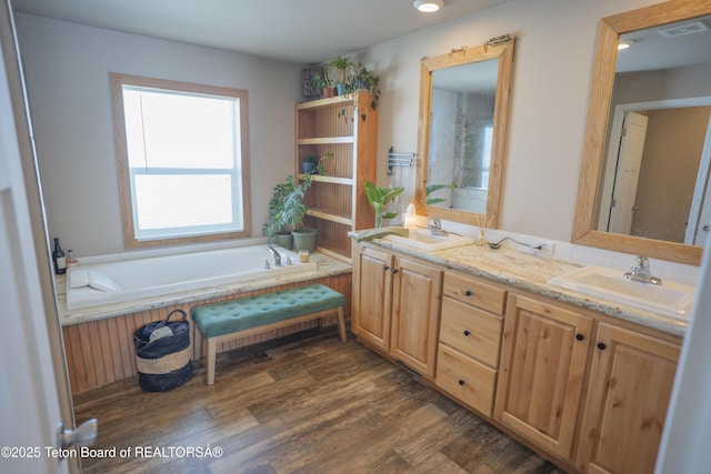 full bathroom featuring double vanity, wood finished floors, visible vents, and a sink