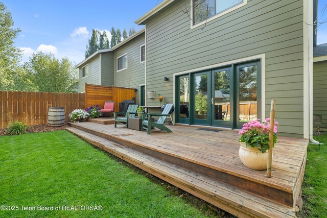 wooden terrace featuring a lawn, french doors, and fence