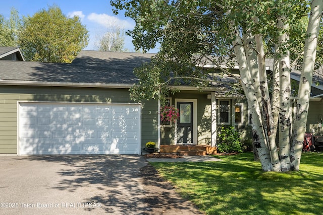 view of front of property with a front lawn, an attached garage, driveway, and a shingled roof