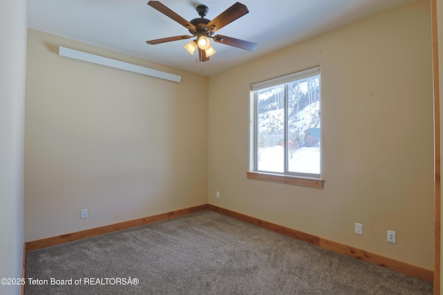 carpeted empty room with a ceiling fan and baseboards