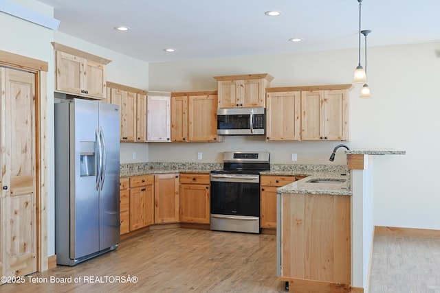 kitchen with light brown cabinets, a peninsula, a sink, stainless steel appliances, and light wood-style floors