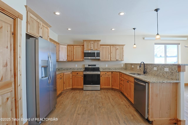 kitchen featuring a sink, a peninsula, light brown cabinetry, and stainless steel appliances