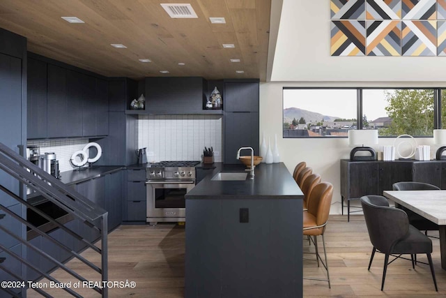 kitchen with visible vents, stainless steel gas range, dark countertops, a kitchen breakfast bar, and modern cabinets