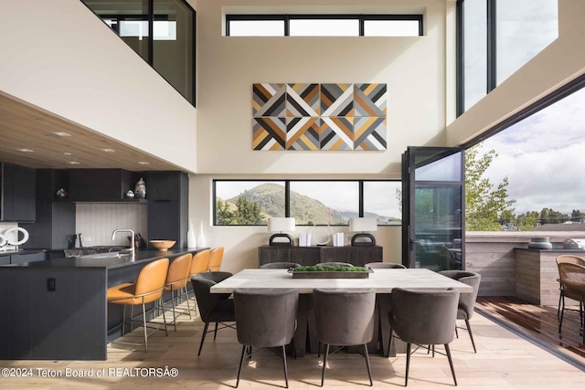 dining space with a high ceiling, plenty of natural light, and light wood-type flooring