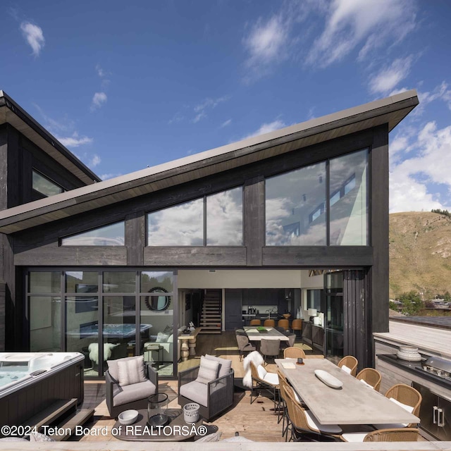 back of house featuring an outdoor living space, a hot tub, and a patio