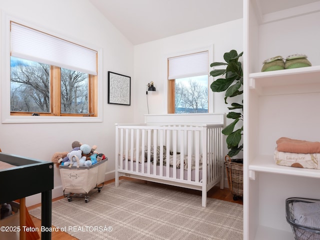 bedroom featuring lofted ceiling, a nursery area, and baseboards