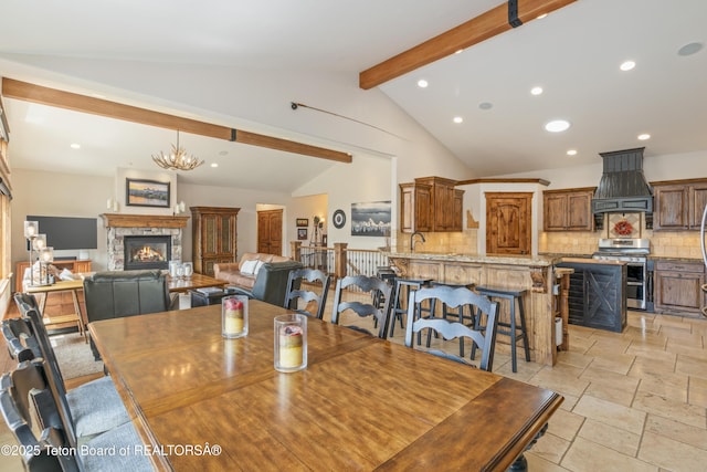 2035 Tomahawk Trl, Victor, ID 83455 - dining area with lofted ceiling with beams, an inviting chandelier, a stone fireplace, recessed lighting, and stone tile flooring