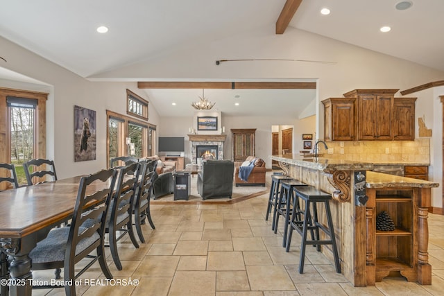 2035 Tomahawk Trl, Victor, ID 83455 - dining room featuring a glass covered fireplace, lofted ceiling with beams, recessed lighting, and a wealth of natural light