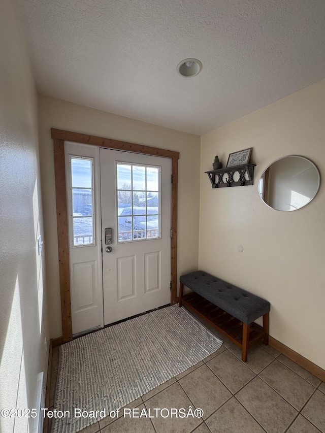 doorway to outside featuring tile patterned flooring, a textured ceiling, and baseboards