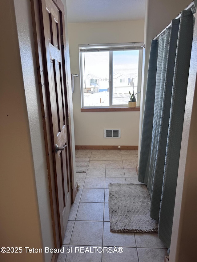 hallway featuring visible vents, baseboards, and tile patterned flooring