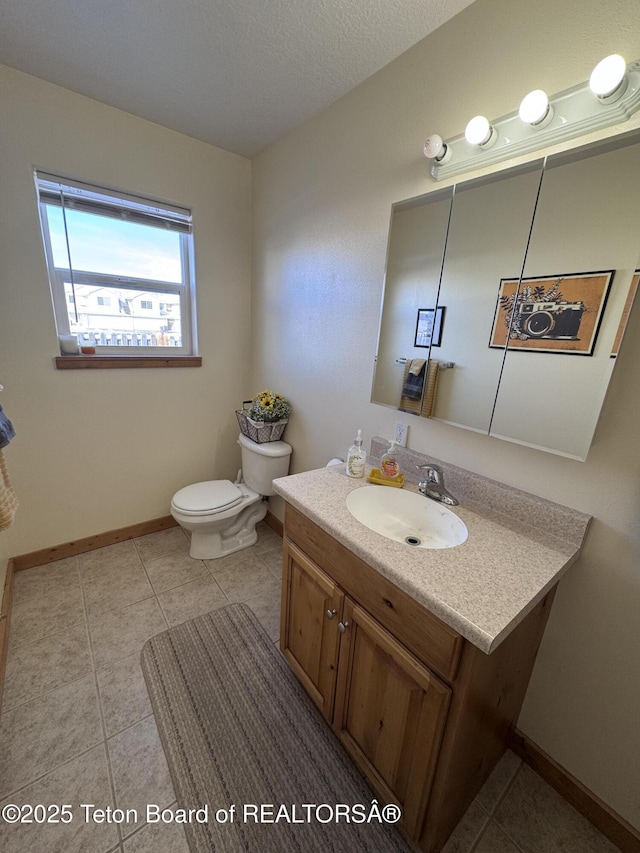 half bathroom with toilet, a textured ceiling, tile patterned flooring, baseboards, and vanity