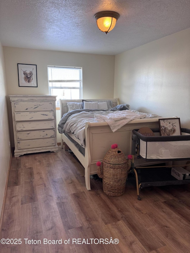 bedroom with a textured ceiling and wood finished floors