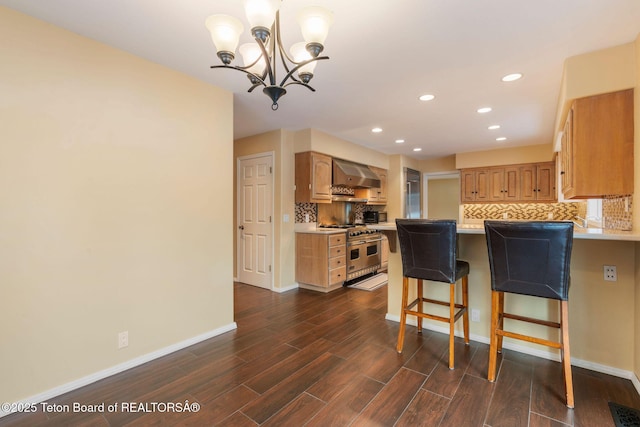 kitchen with double oven range, dark wood finished floors, wall chimney exhaust hood, light countertops, and decorative backsplash