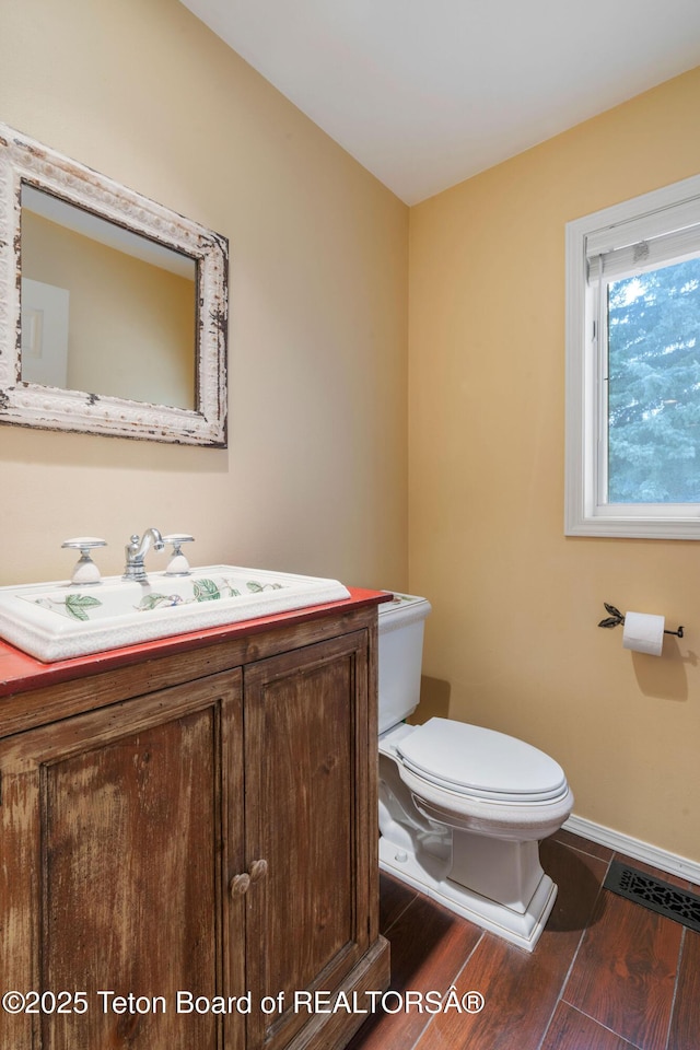 bathroom with visible vents, toilet, wood finished floors, baseboards, and vanity