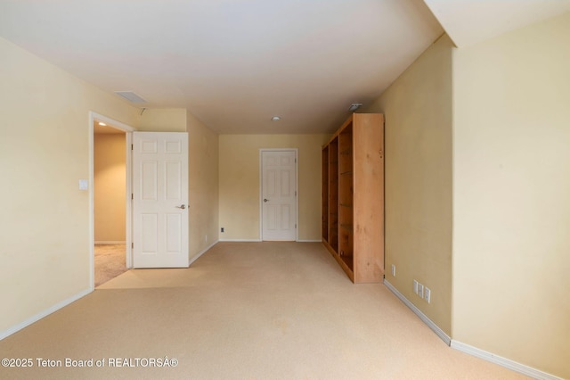 unfurnished bedroom with baseboards, light carpet, and visible vents