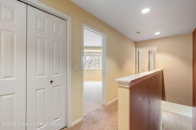 hallway with recessed lighting, light colored carpet, and baseboards