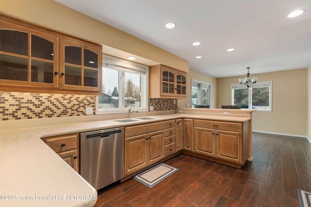 kitchen featuring a sink, light countertops, stainless steel dishwasher, a notable chandelier, and tasteful backsplash