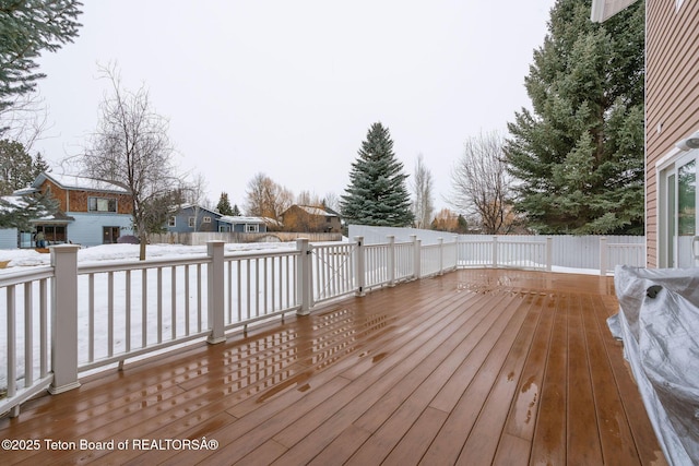 snow covered deck with a fenced backyard