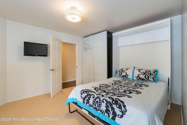 bedroom featuring light colored carpet, baseboards, and a closet