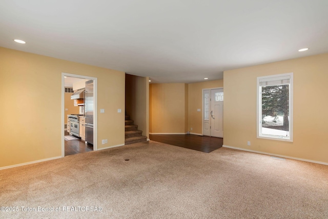 unfurnished living room featuring stairs, baseboards, recessed lighting, and carpet flooring