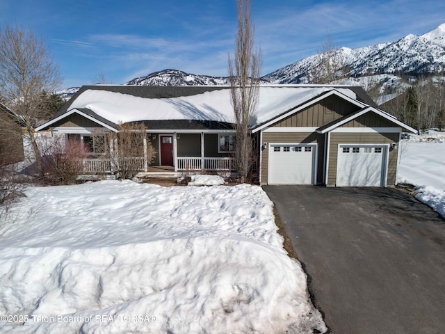 view of front of home with a mountain view, an attached garage, covered porch, aphalt driveway, and board and batten siding