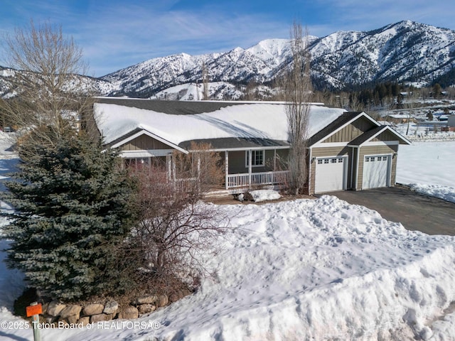 ranch-style home with driveway, a mountain view, an attached garage, covered porch, and board and batten siding