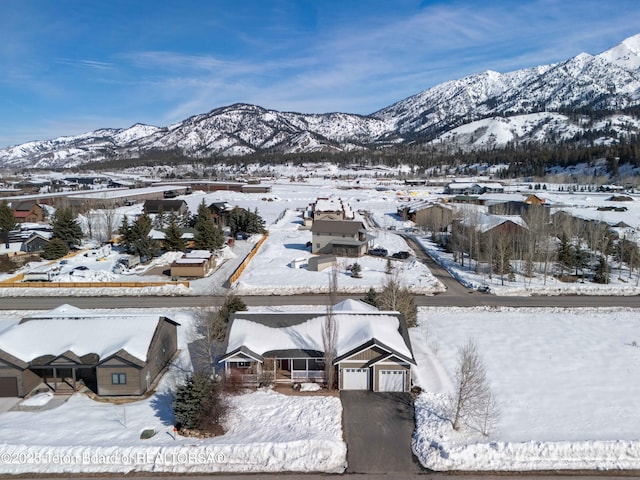 snowy aerial view featuring a residential view and a mountain view