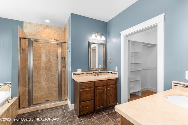 bathroom with a spacious closet, a stall shower, vanity, and a bath