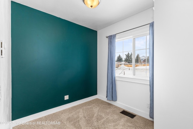 empty room featuring visible vents, carpet floors, and baseboards