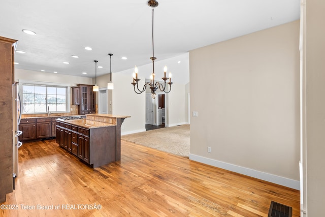 kitchen featuring visible vents, light wood finished floors, baseboards, a chandelier, and stainless steel gas cooktop