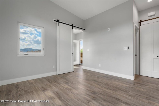 138 Larkspur Ave Unit 402, Victor, ID 83455 - unfurnished bedroom with a barn door, wood finished floors, and high vaulted ceiling